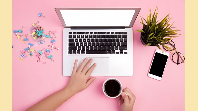 close-up-hand-working-with-laptop-on-pink-table