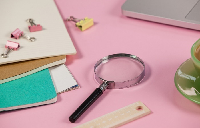 magnifying-glass-and-random-objects-on-pink-table-